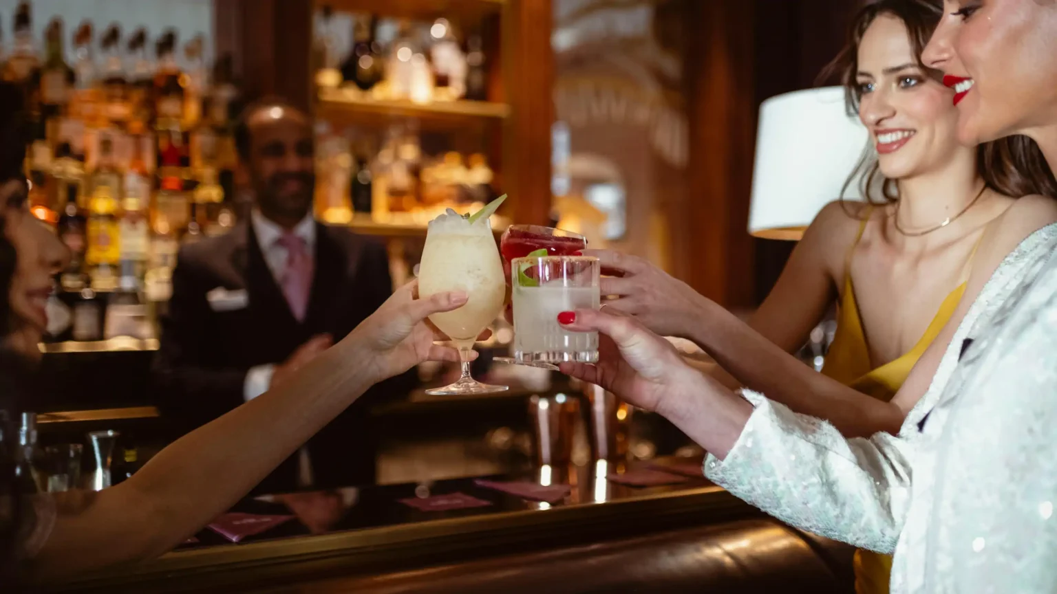 kobieta i mężczyzna dotykają się kieliszkami z drinkami w barze hotelowym