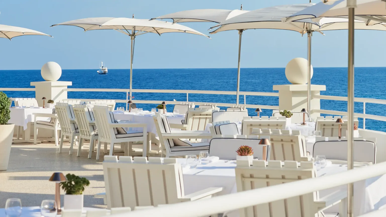 taras hotelowy z białymi meblami i parasolami z widokiem na morze