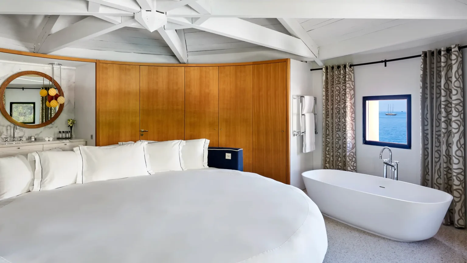 duże białe łóżko w półokrągłym pokoju hotelowym