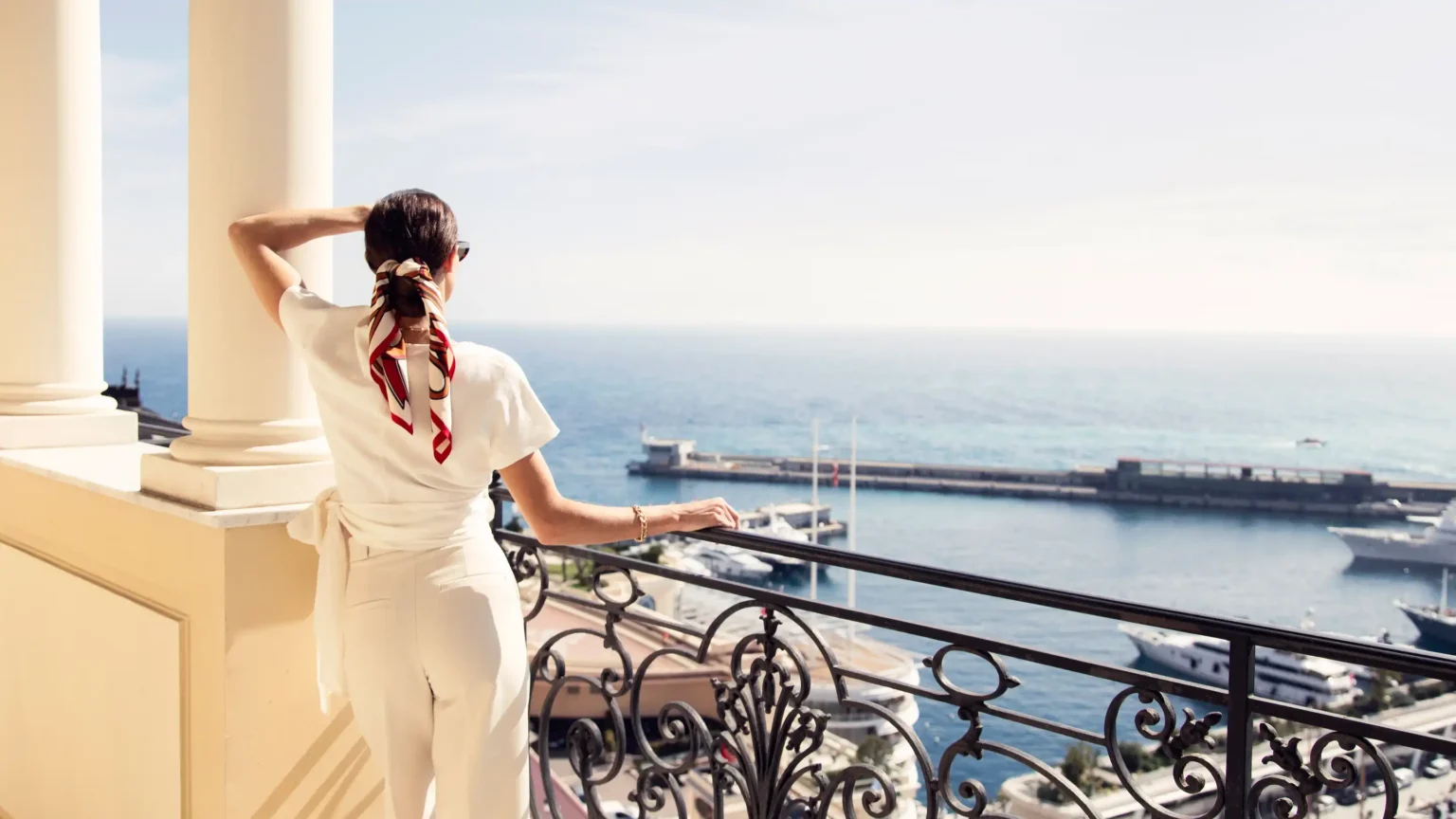 kobieta stojąca na balkonie hotelowym z widokiem na ocean