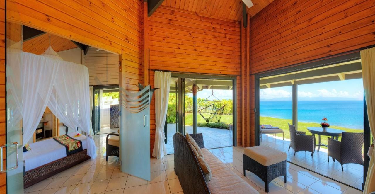 zdjęcie przedstawia przykładową sypialnie połączoną z tarasem na otwartą przestrzeń z widokiem na ocean w taveuni island resort & spa