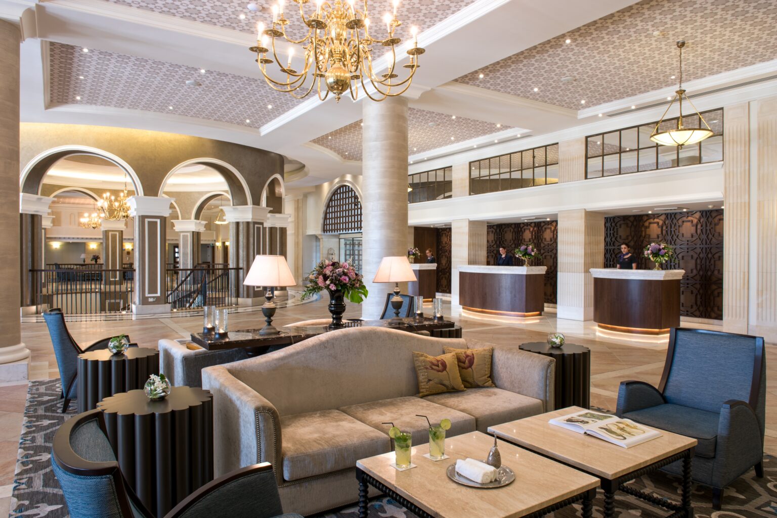 Pokój wypoczynkowy, wzorzysty dywan kanapa w jasnym kolorze i ozdobna lampa sufitowa