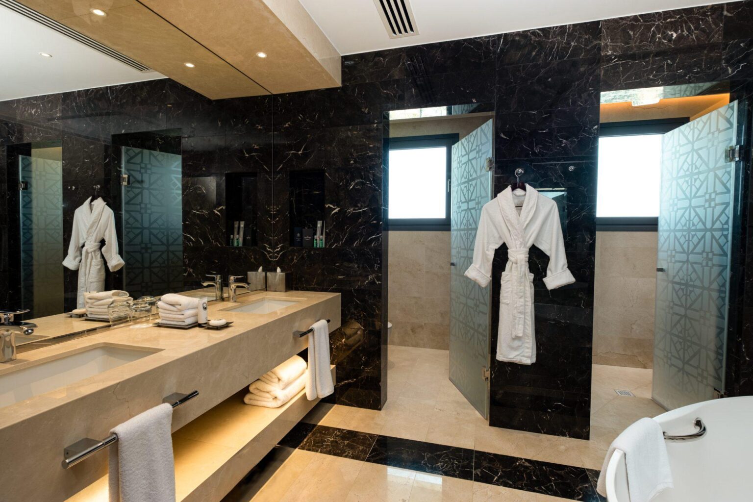 łazienka w hotelu Parklane, a Luxury Collection Resort & Spa, wiszący szlafrok na ciemnej ścianie