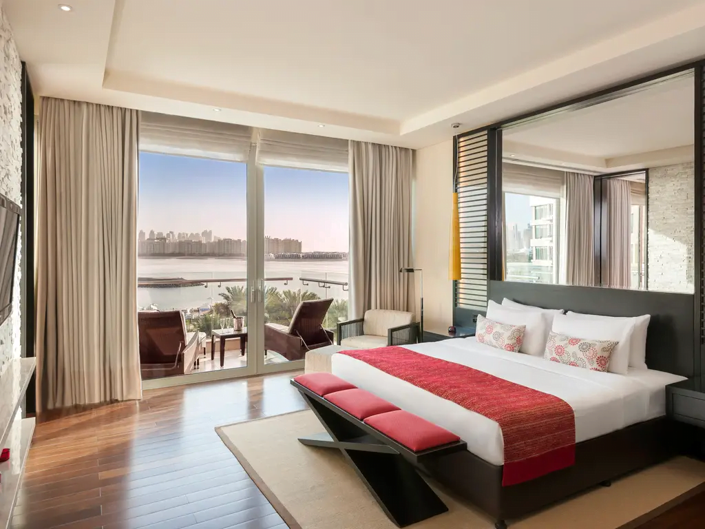 sypialnia z duzymi oknami na zatokę, jasne wnętrzne z czerwonymi akcentami w Rixos The Palm Hotel & Suites - Ultra All-inclusive