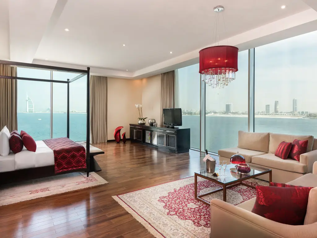 sypialnia z duzymi oknami na zatokę, jasne wnętrzne z czerwonymi akcentami w Rixos The Palm Hotel & Suites - Ultra All-inclusive