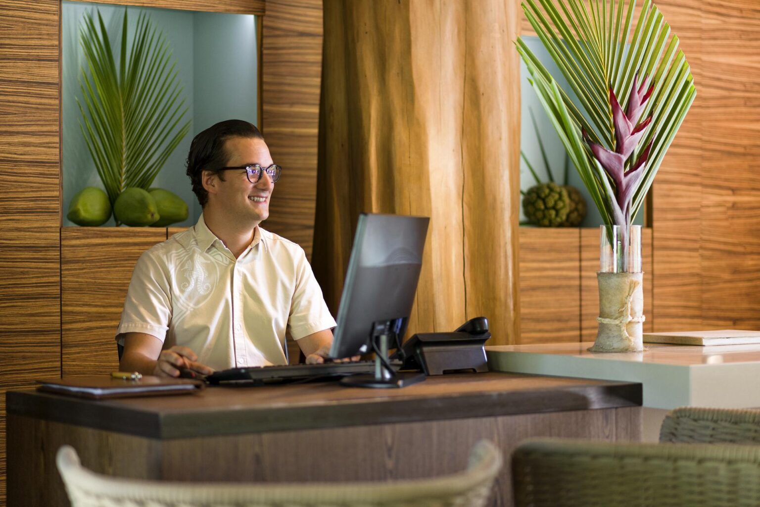 mężczyzna siedzący w hotelowej recepcji przed laptopem
