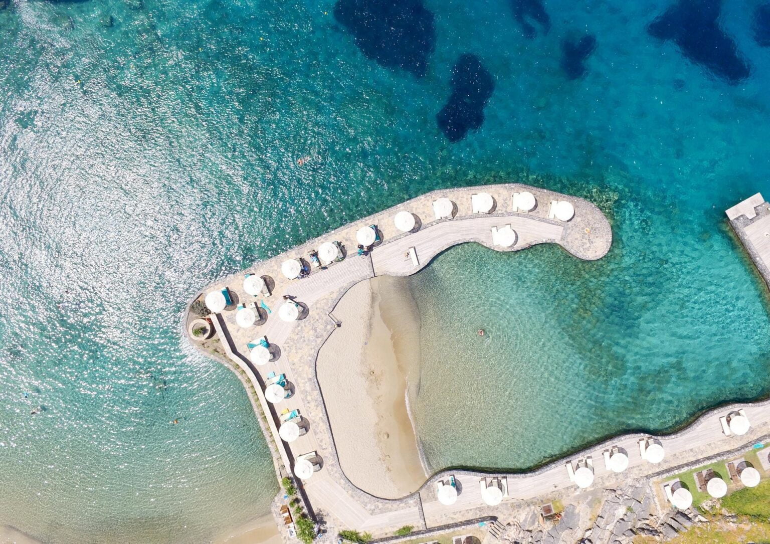 Elounda Peninsula Luxury Resort zatoka na plaży z lotu ptaka, leżaki ustawione na wodzie