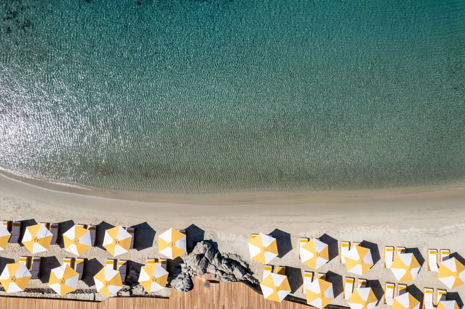 Santa Marina Mykonos, a private beach from a bird's eye view, with sun loungers and umbrellas