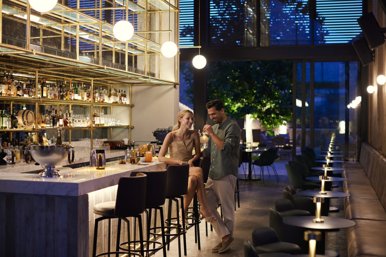 podświetlony bar w hotelu, dwoje ludzi spędzający czas i rozmawiający ze sobą