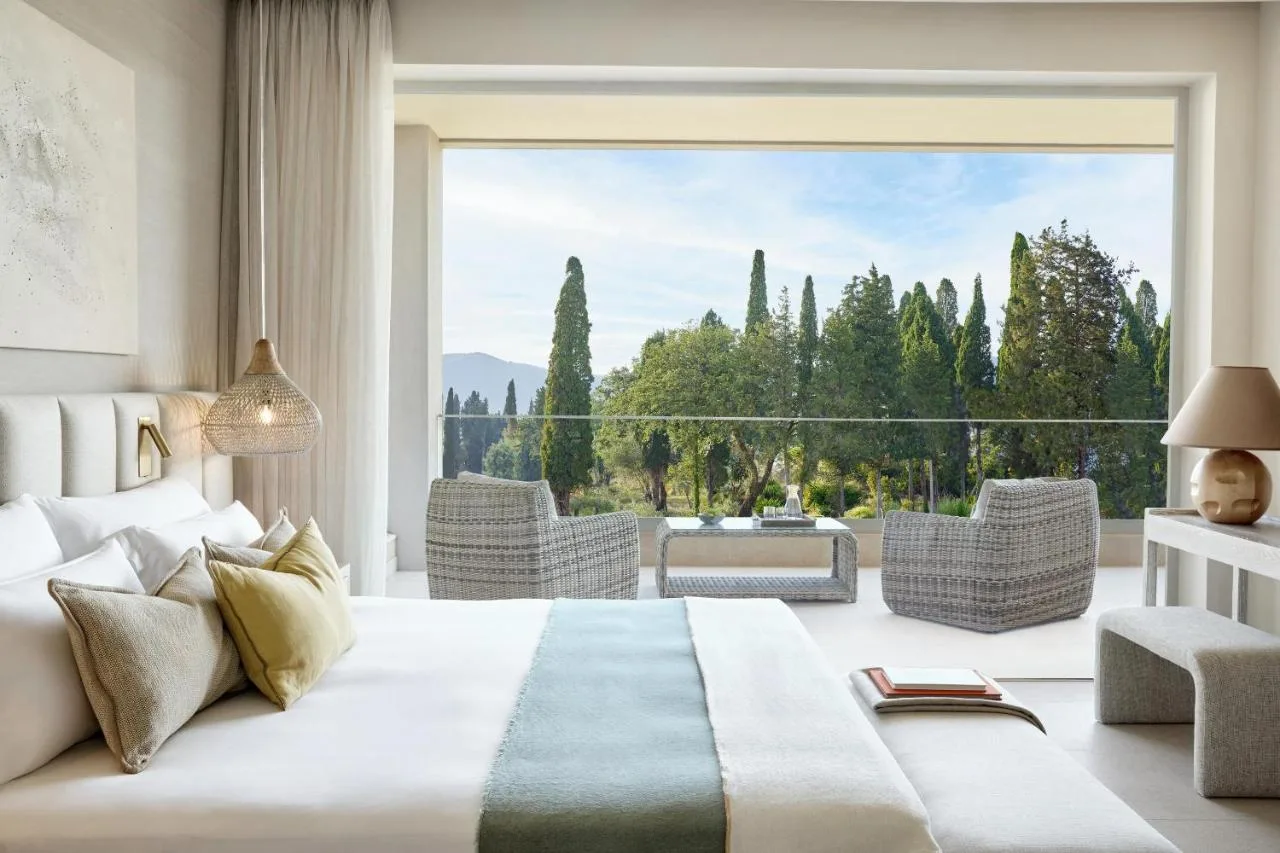 Przykładowa sypialnia w jasnym, beżowym odcieniu w Ikos Odisia z widokiem na ogrody