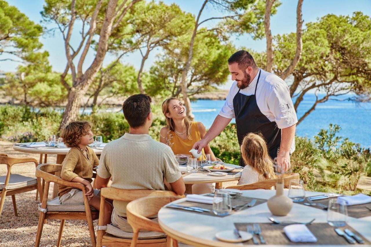 Rodzina przebywająca w restauracji hotelu Ikos Odisia rozmawiająca z szefem kuchni serwującym dania