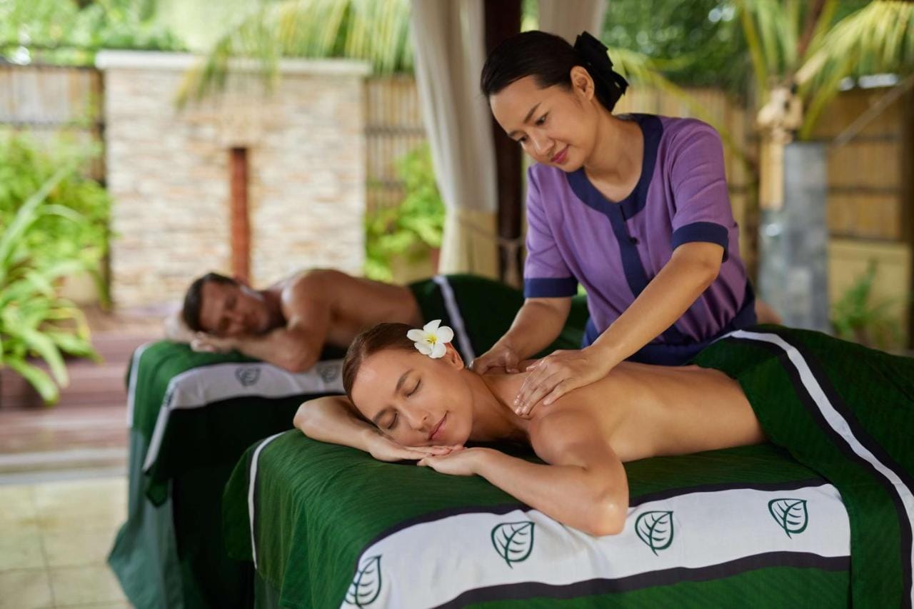 mężczyzna i kobieta odpoczywający w spa - kobieta jest masowana przez masażystkę