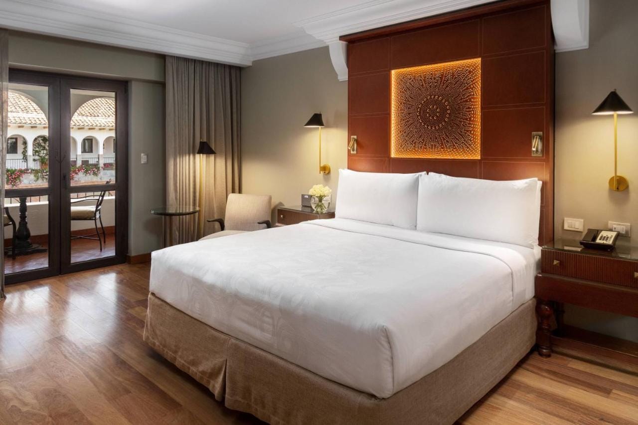 jw marriott el convento cusco przykładowa sypialnia w barwach brązu i szarości, duże podwójne łóżko