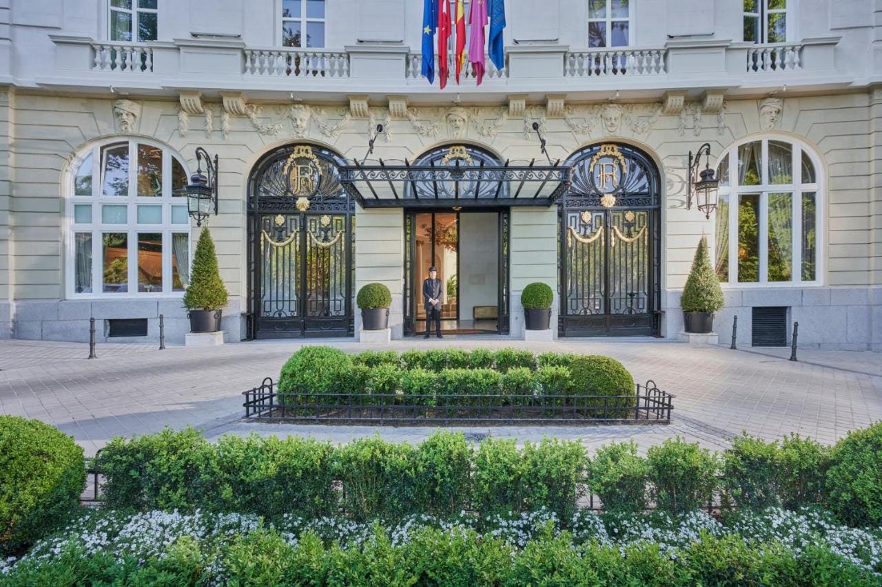 Zdjęcie przedstawia widok na wejście do hotelu w otoczeniu zieleni mandarin oriental ritz, madrid