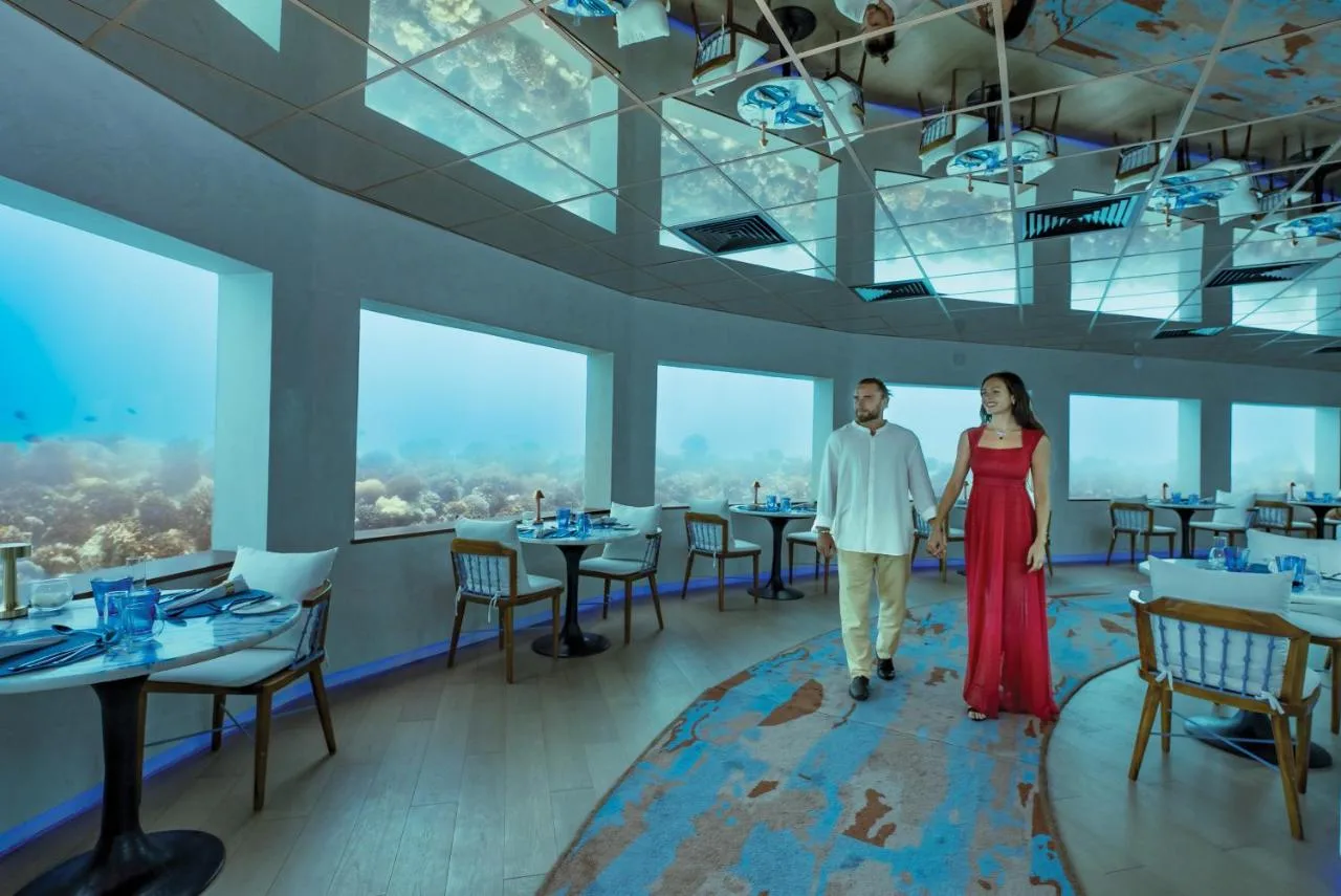 man and woman walking around underwater restaurant at oblu select lobigili premium all inclusive