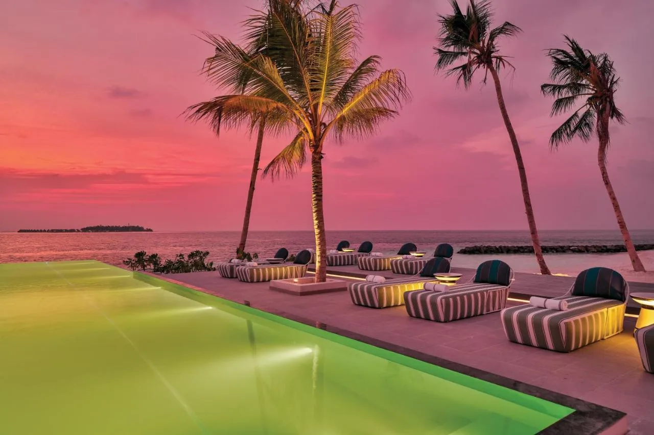 illuminated swimming pool overlooking the vast ocean at sunset oblu select lobigili premium all inclusive