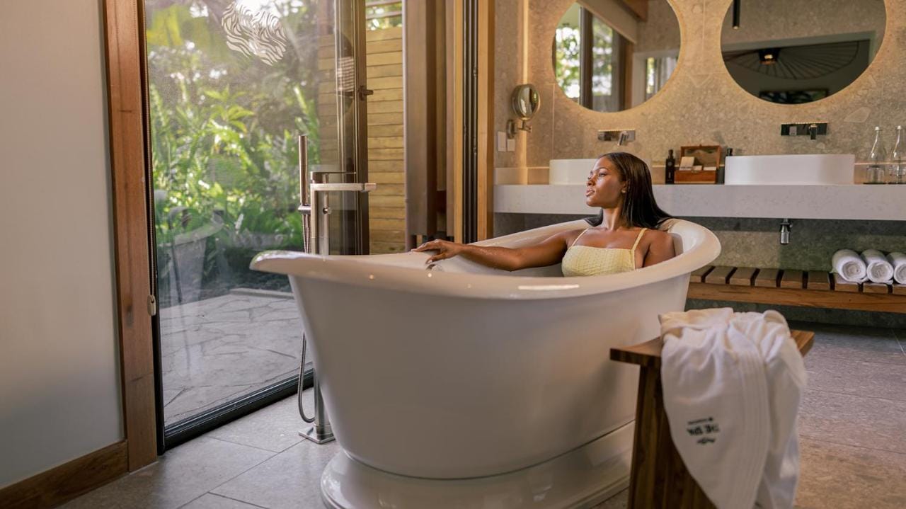 kobieta siedząca w wannie patrząca przez okno w apartamencie tabacón thermal resort & spa