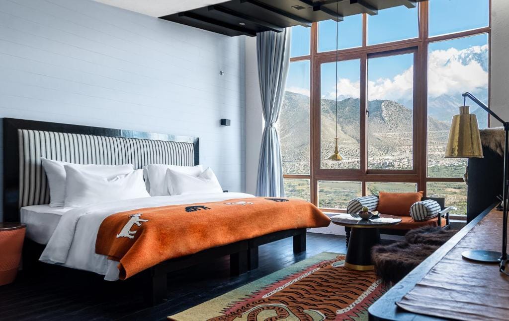 shinta mani mustang sypialnia w pomaranczowych akcentach i ciemnym drewnie, duze lozko z widokiem na gory