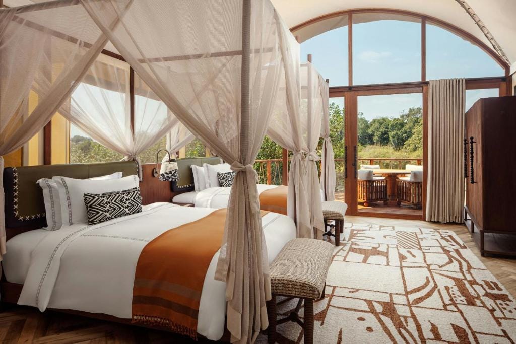 the ritz carlton masai mara safari camp duża sypialnia z baldachimami i widokiem na przyrodę