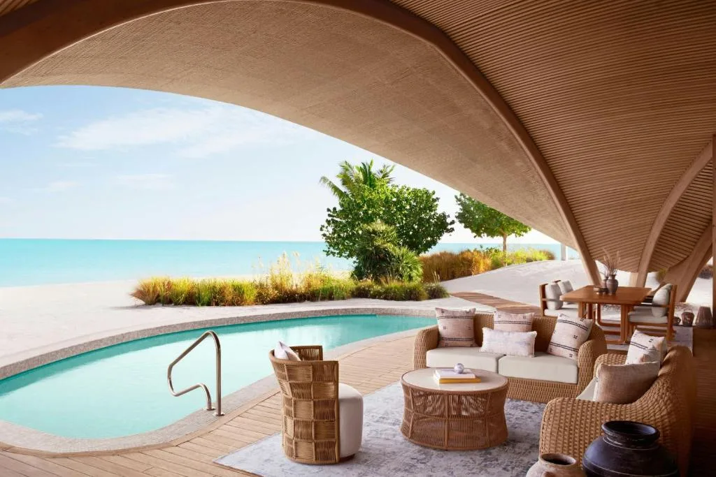 nujuma a ritz carlton reserve pool by the cottage with a roof