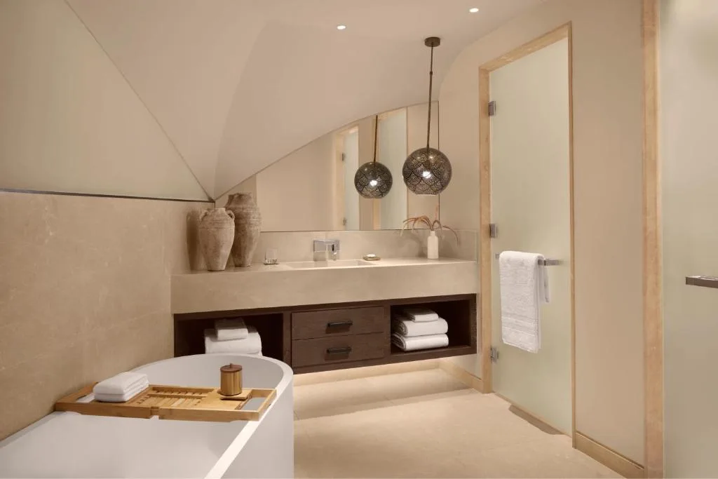 nujuma a ritz carlton reserve bathroom with bathtub - light beige colors with a dark wood accent
