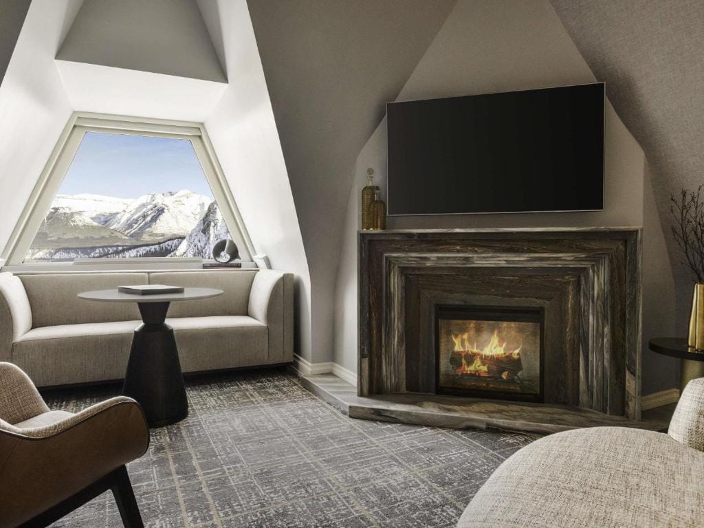 Камин и место у окна в отеле Fairmont Banff Springs с видом на горы.