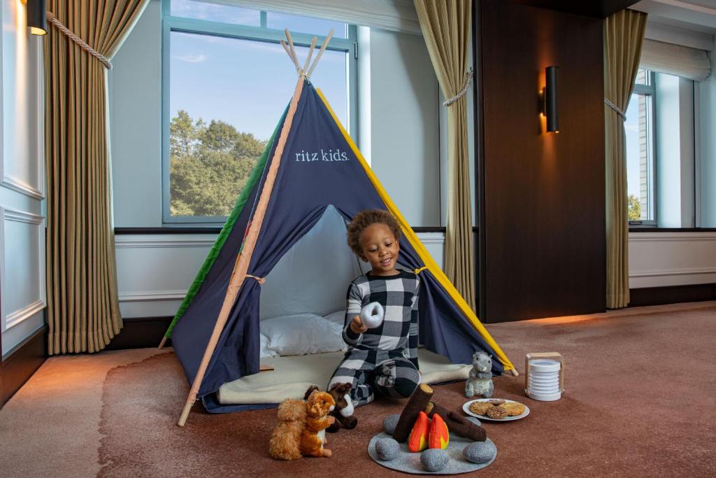 the ritz carlton new york central park dziecko bawiące się wpokoju, w namiocie, zabawkami oferowanymi przez hotel