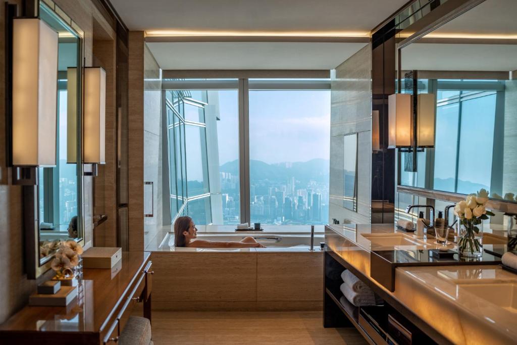 the ritz carlton hong kong wanna z widokiem na miasto - kobieta podziwiająca widoki
